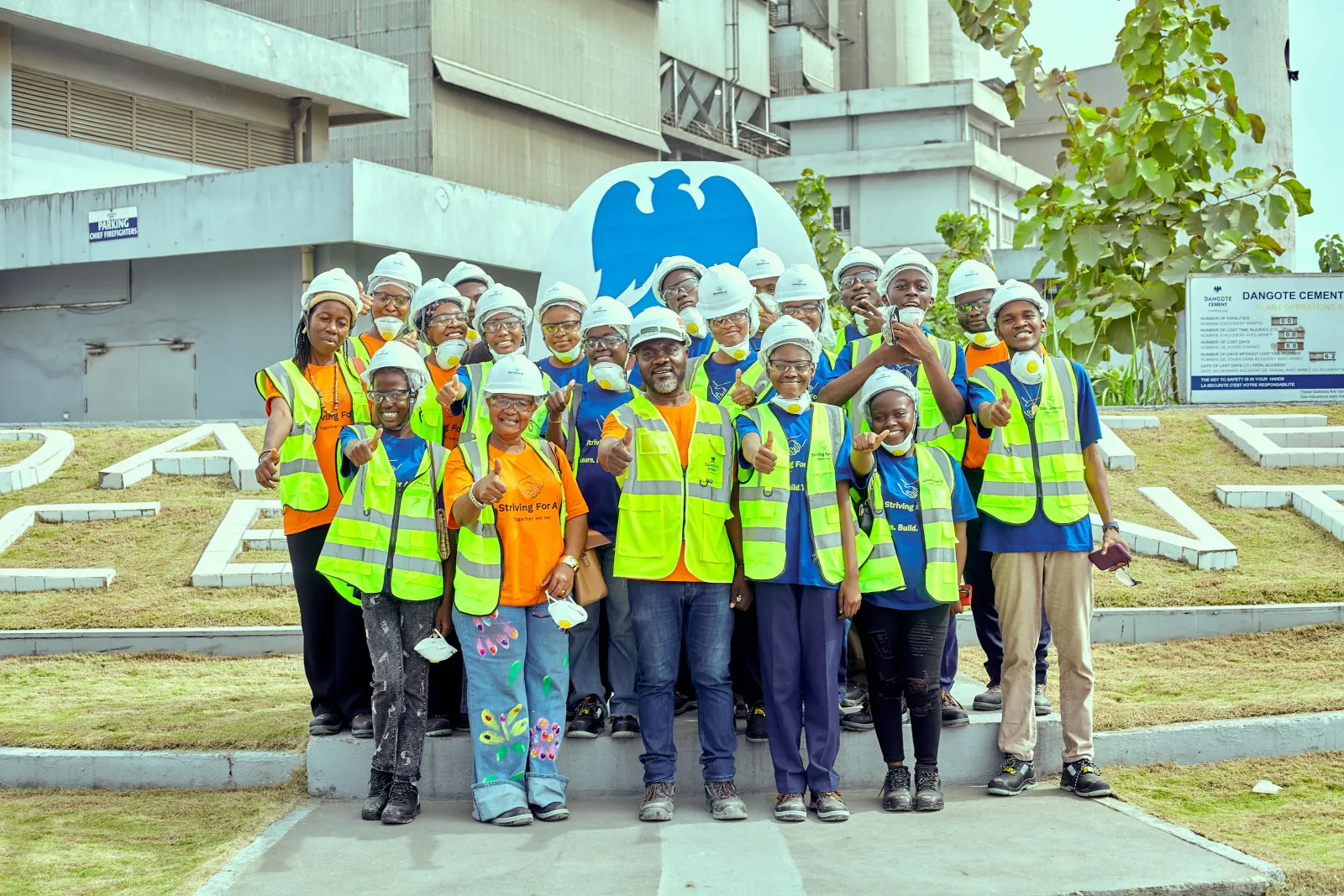 Woker and students posing for a photo in front of Dangote factory
