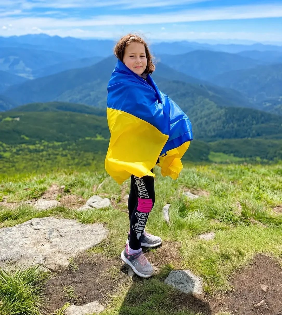 Ukrainian girl standing on hill holding the Ukrainian flag