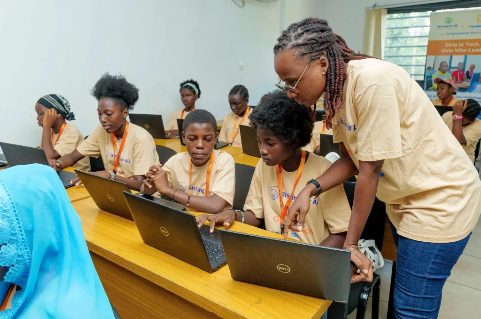 Teacher guiding girls working on pc